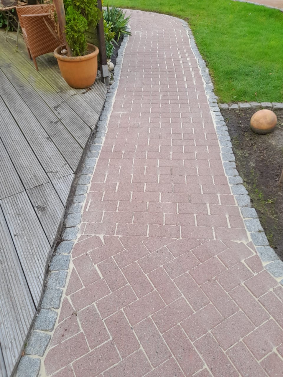 Derselbe geschwungene Gartenweg nach Reinigung und Fugenbearbeitung